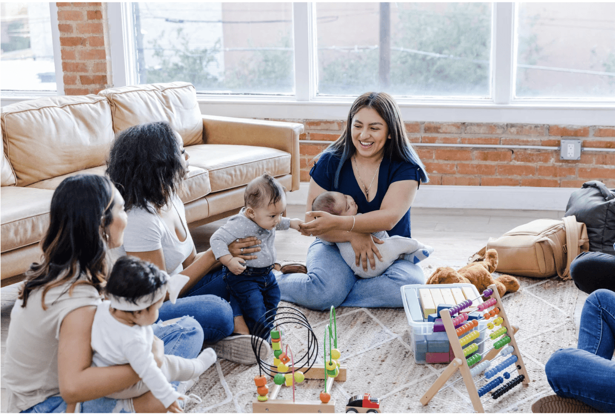 Three moms sit in a circle with their young babies on their laps